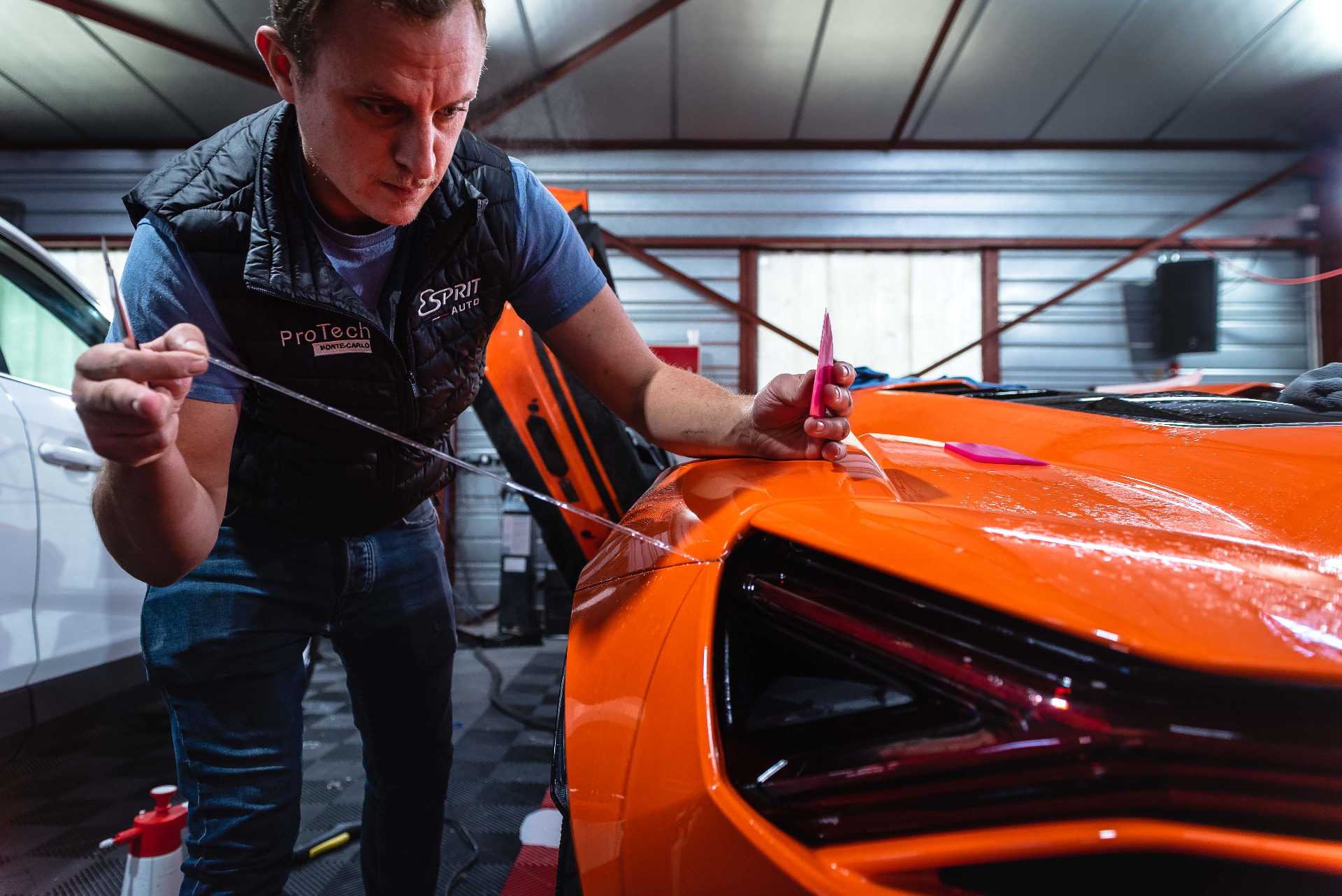 Technicien posant un film de protection sur une Lamborghini Revuelto orange