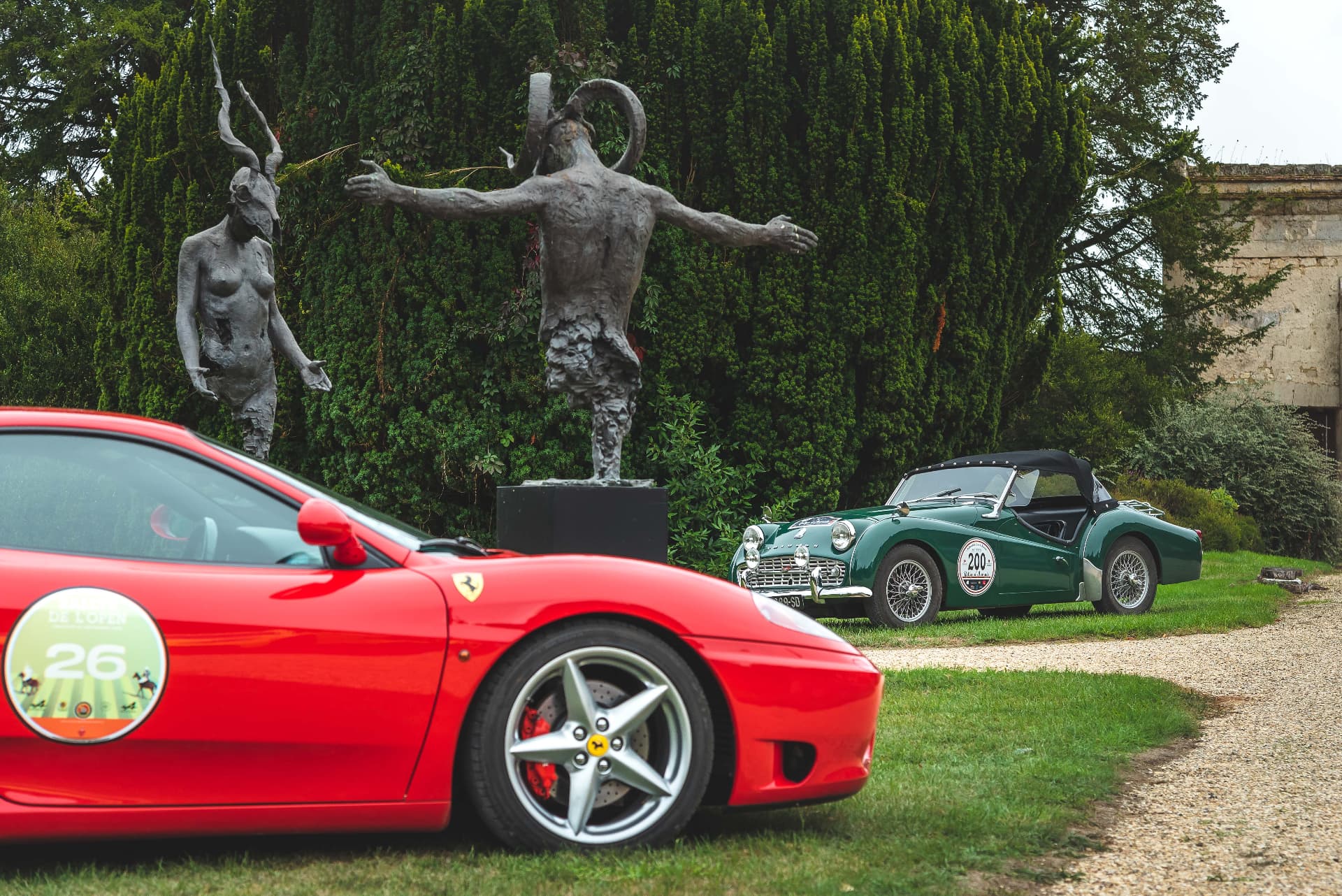 Ferrari rouge et Triumph verte parmi les sculptures Lug et Gaia