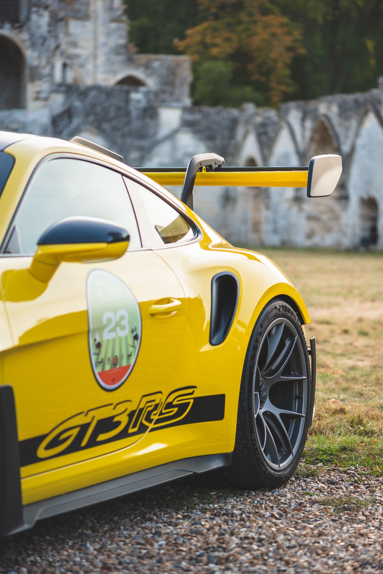 Détail d'une Porsche jaune au pied de ruines en pierre