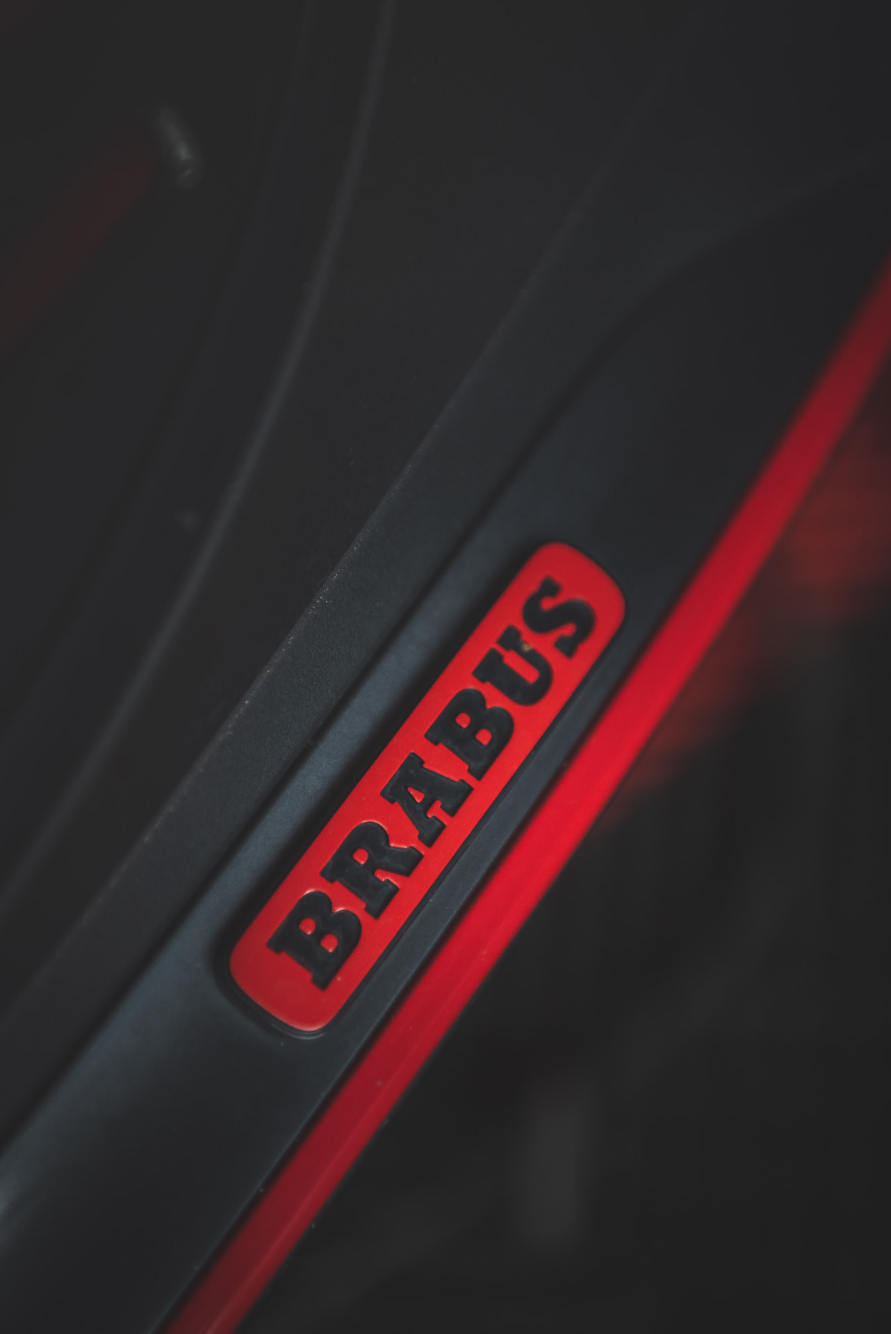 Détail du badge Brabus rouge sur un liseré de carrosserie noire