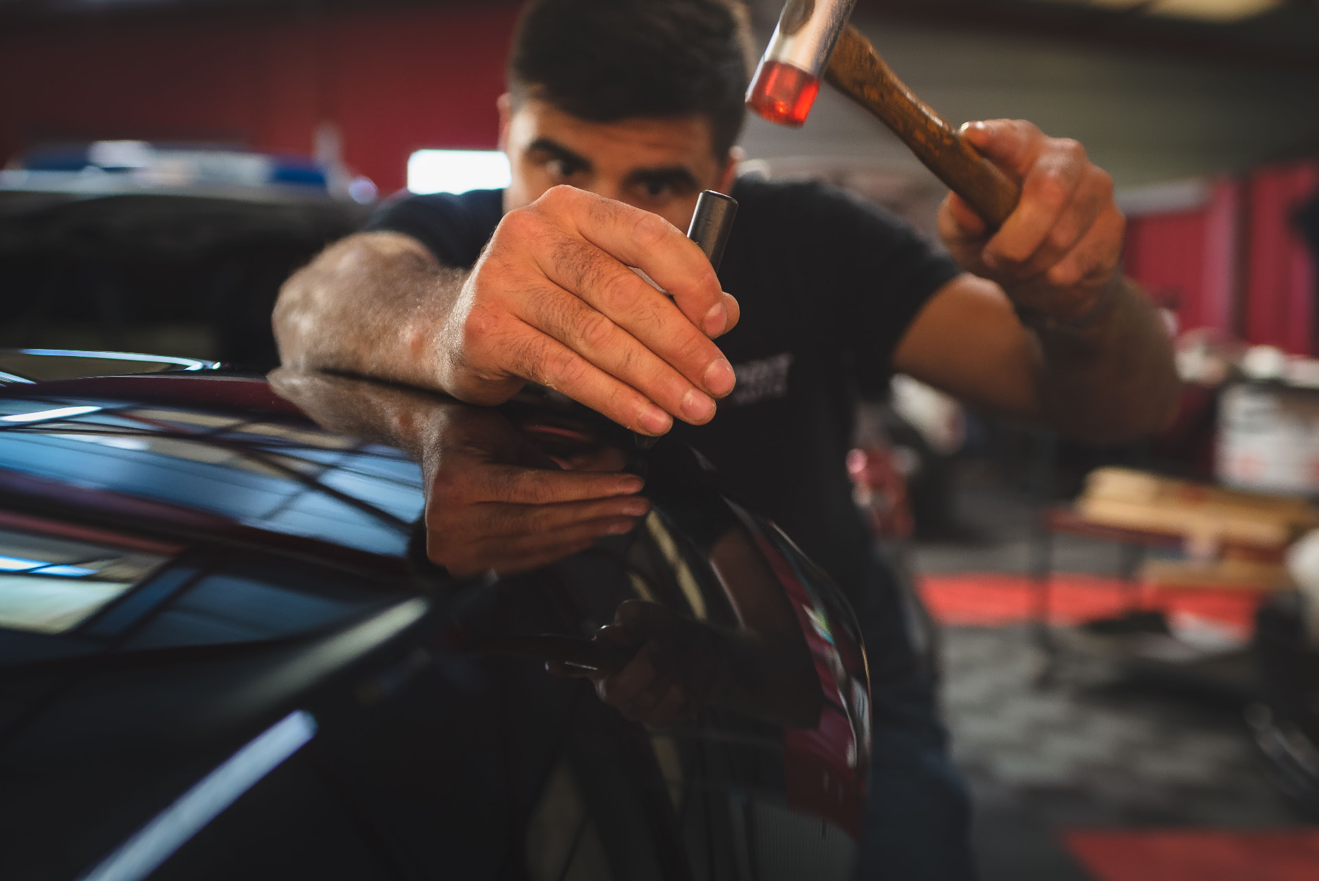 Débosselage sans peinture réalisé au marteau sur une carrosserie sombre