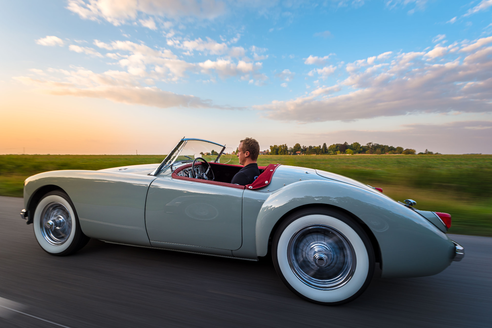 MGA cabriolet roulant sur une route au coucher du soleil — Esprit Auto
