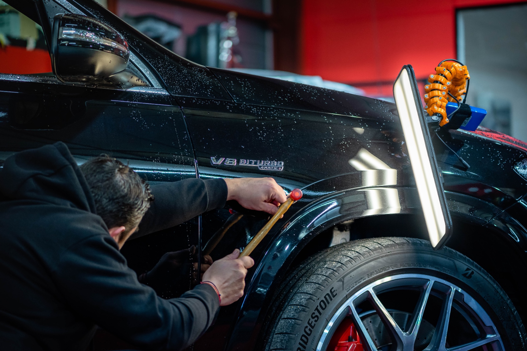 Axel travaillant sur une carrosserie noire avec une barre de lumière