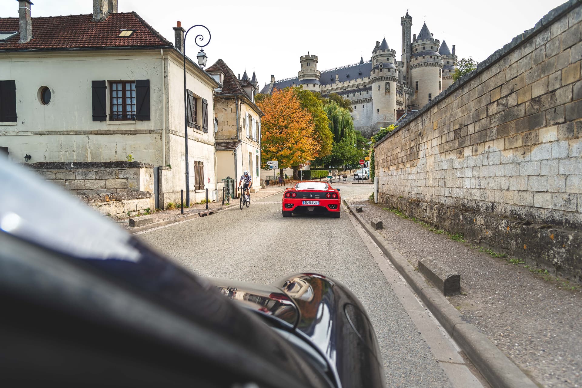 Ferrari rouge roulant vers un château