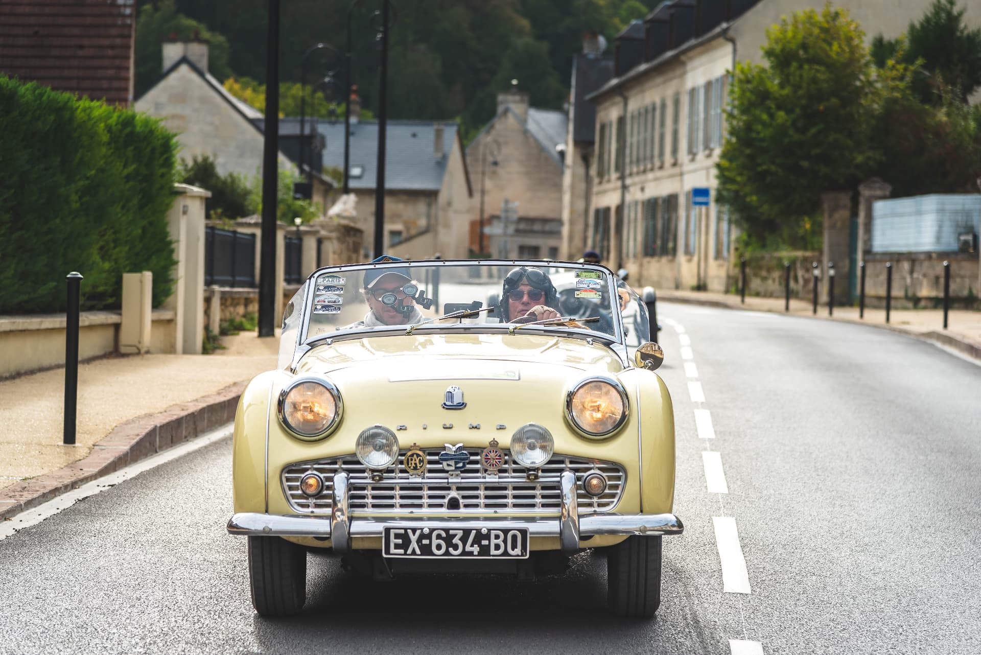 Roadster crème traversant un village