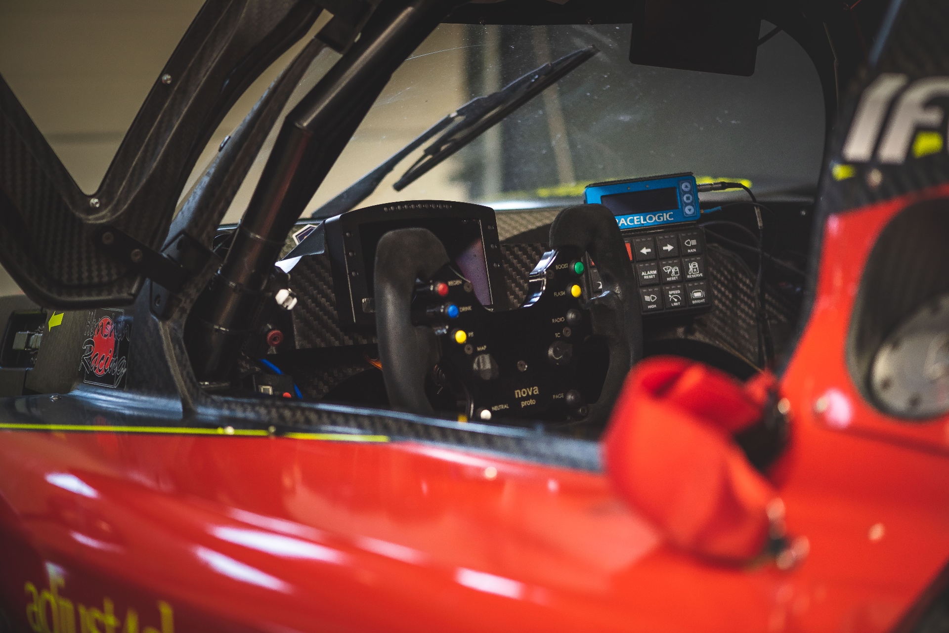 Cockpit carbone et carrosserie rouge, vue latérale sur le volant