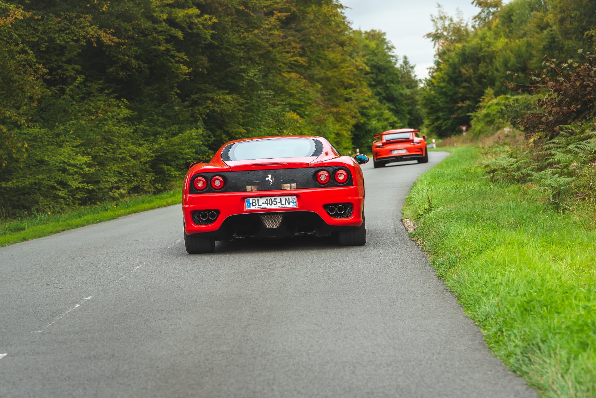Deux Ferrari rouges sur une route forestière