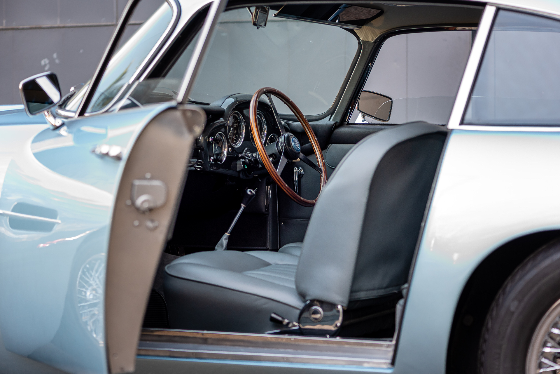 Aston Martin DB4 — intérieur cuir gris restauré, volant en bois, porte ouverte