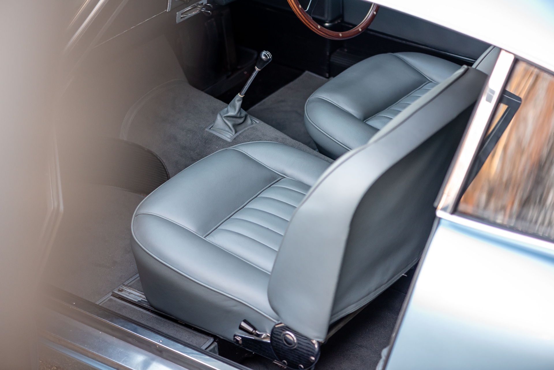 Habitacle Aston Martin DB4, deux sièges cuir gris-bleu et levier de vitesse