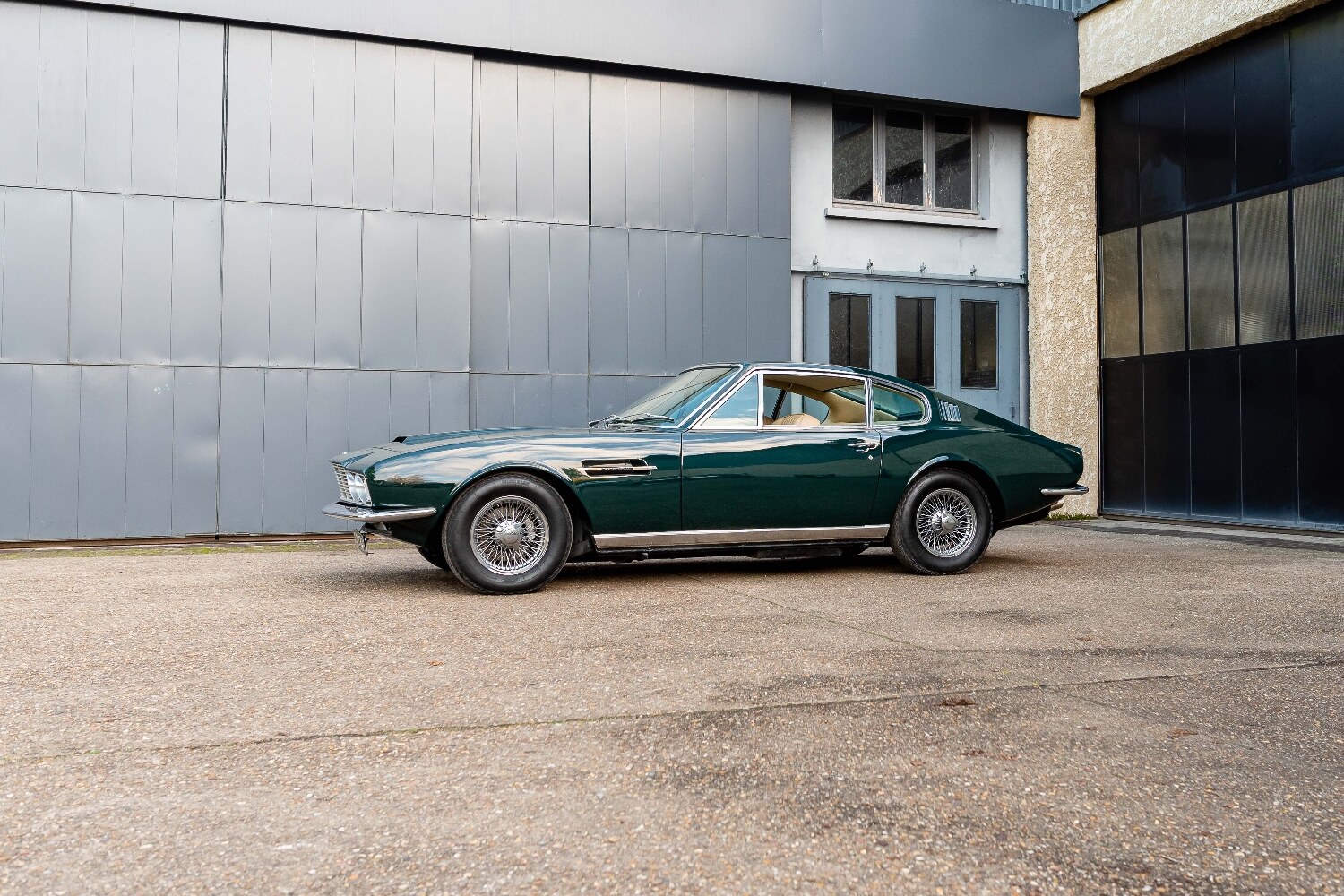 Aston Martin DBS verte devant atelier