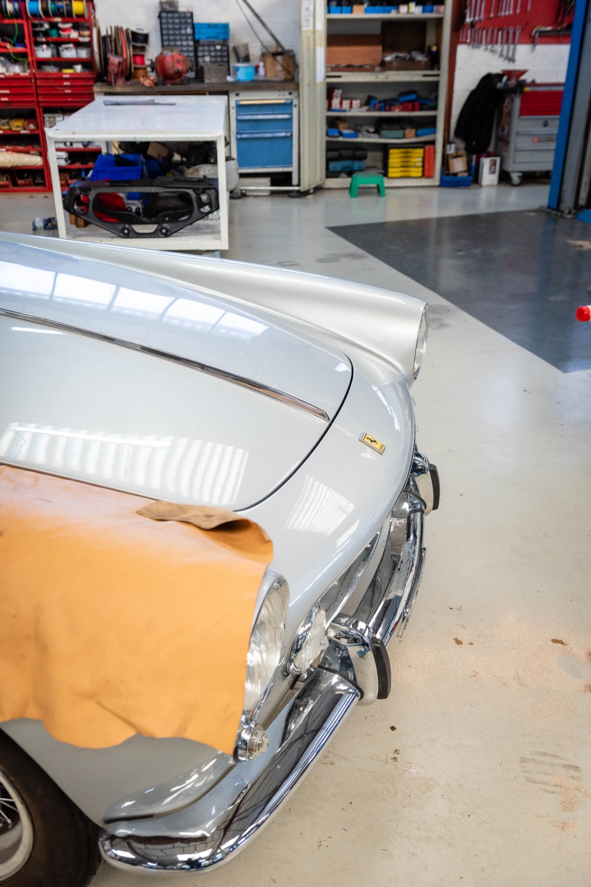 Peau de cuir posée sur l'aile d'une voiture grise dans l'atelier Cecil Cars