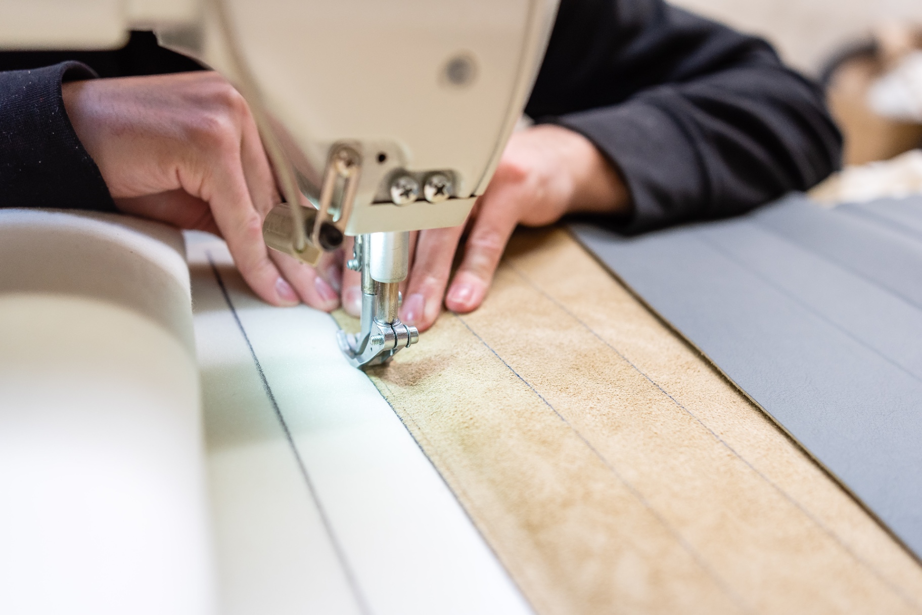 Mains guidant le cuir sous l'aiguille de la machine à coudre