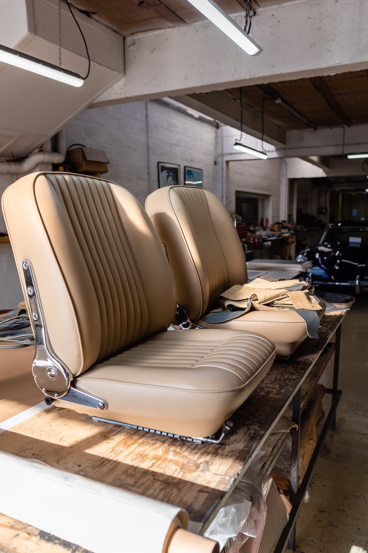 Sièges en cuir beige fraîchement habillés, atelier Cecil Cars, Jaguar noire en arrière-plan