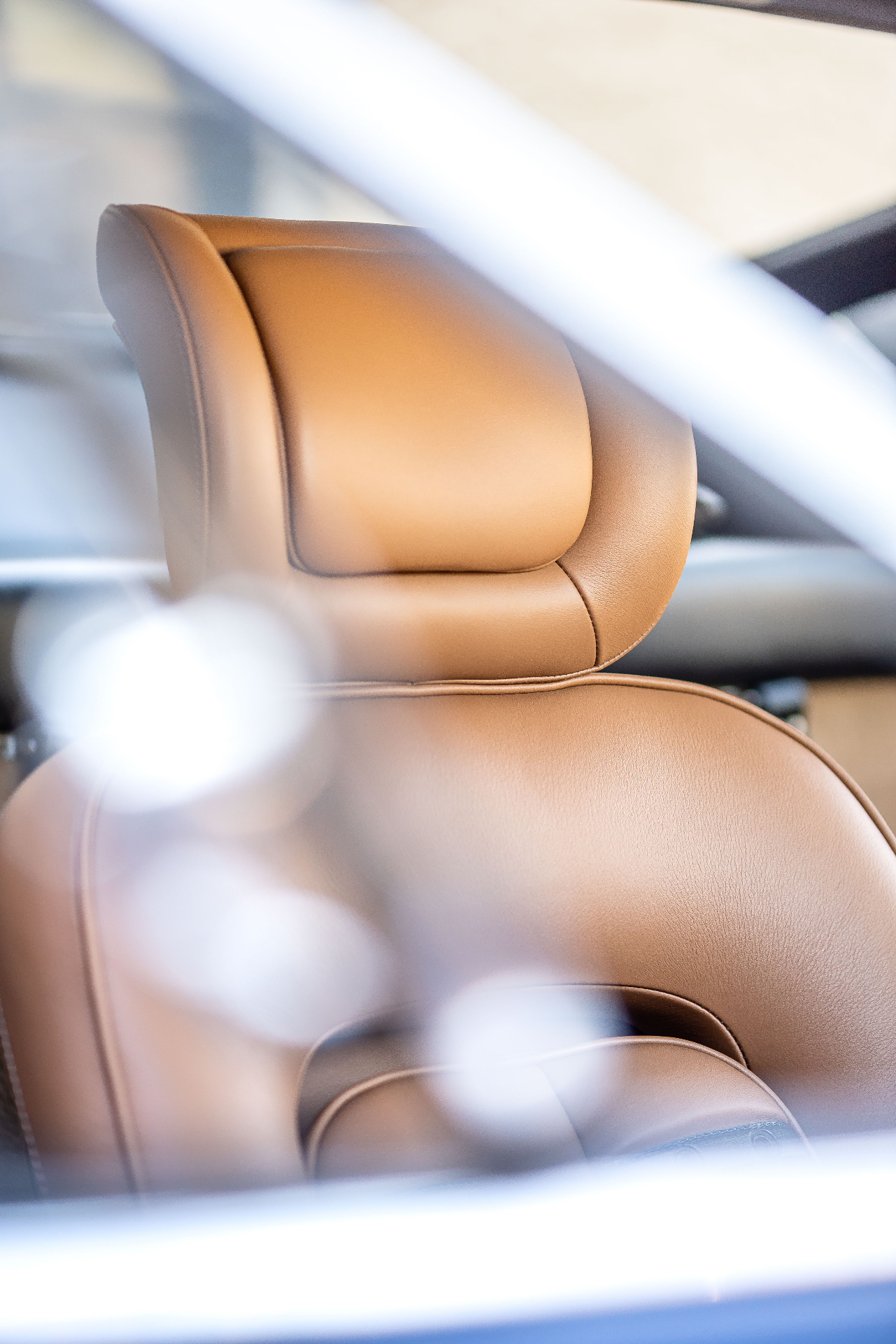 Appui-tête cuir cognac, gros plan onirique à travers le volant