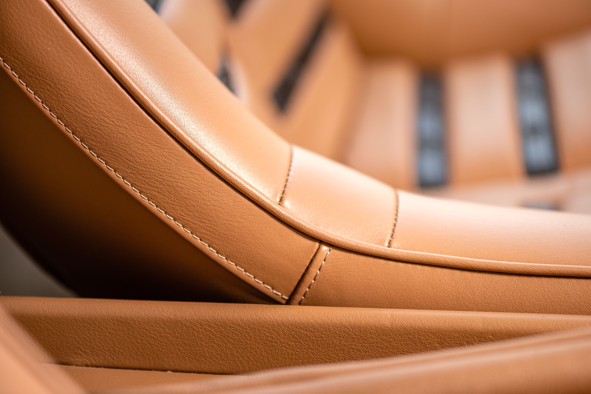 Ferrari Daytona — détail macro de la sellerie cuir cognac, surpiqûres