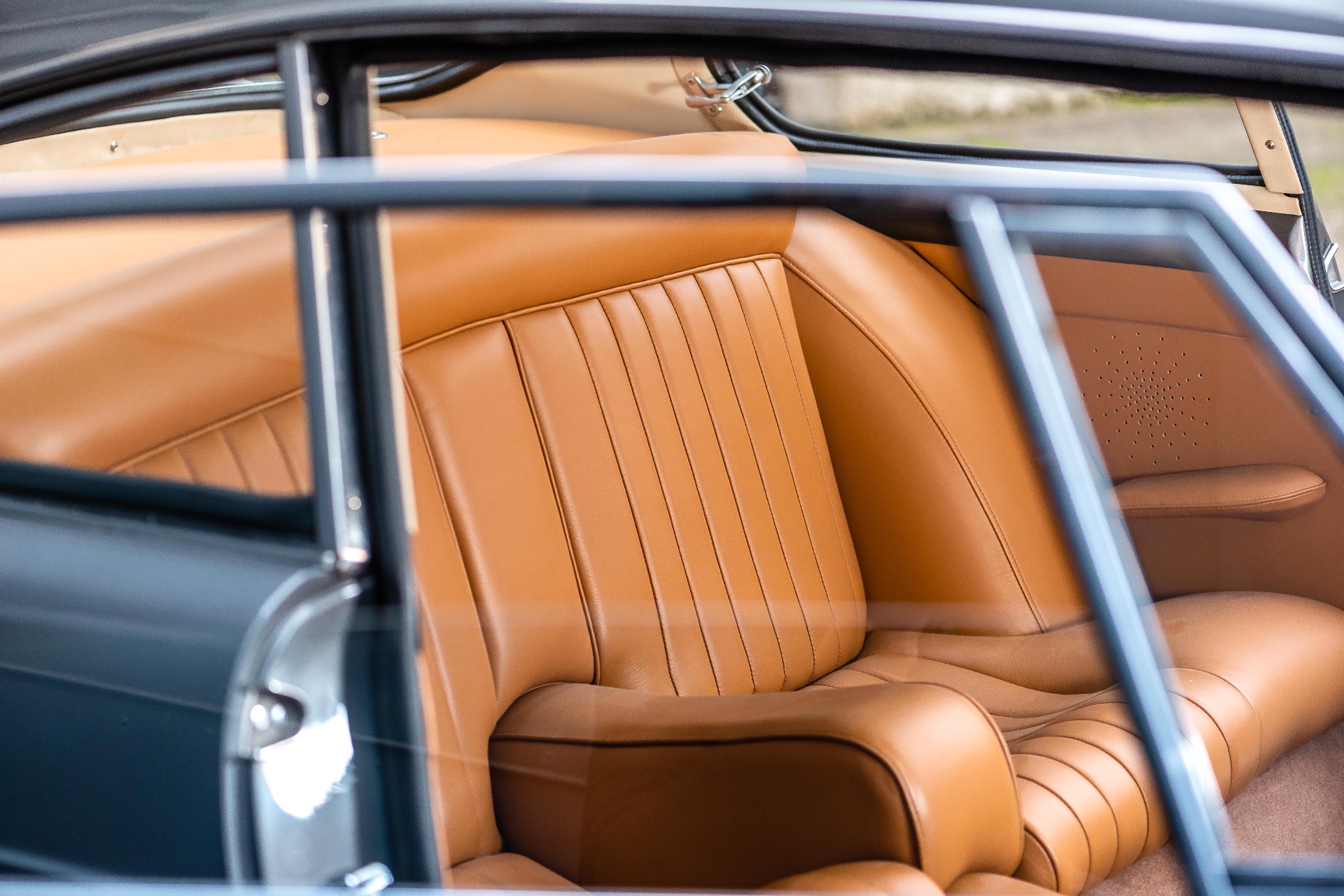 Banquette arrière en cuir camel d'une Ferrari 250 GTE, vue à travers les vitres