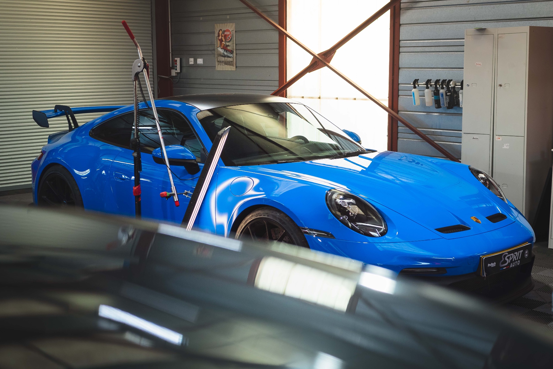 Porsche 911 GT3 bleue dans l'atelier Esprit Auto, lumière de fin de journée