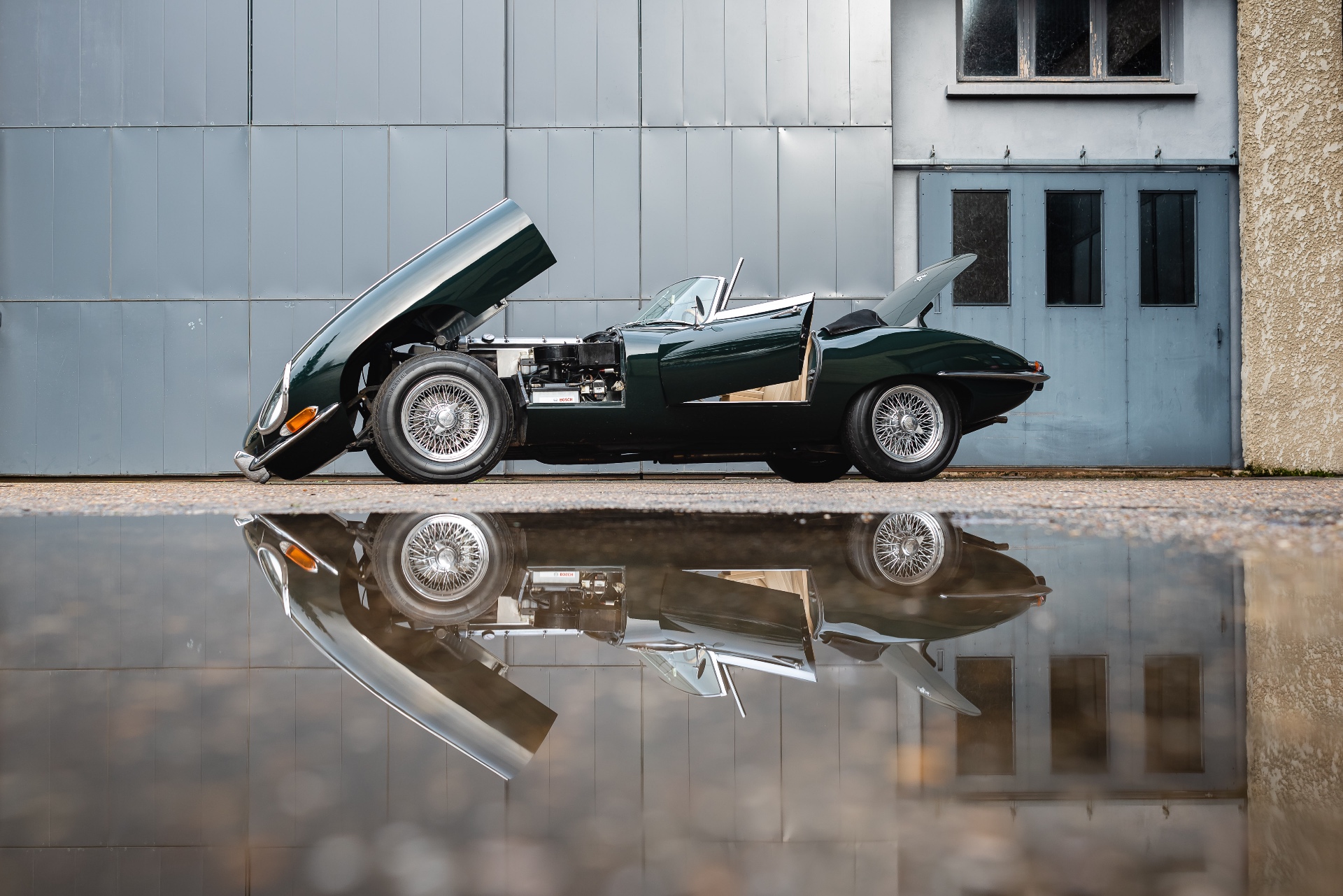Jaguar Type E verte de profil, capot et coffre ouverts, reflet au sol