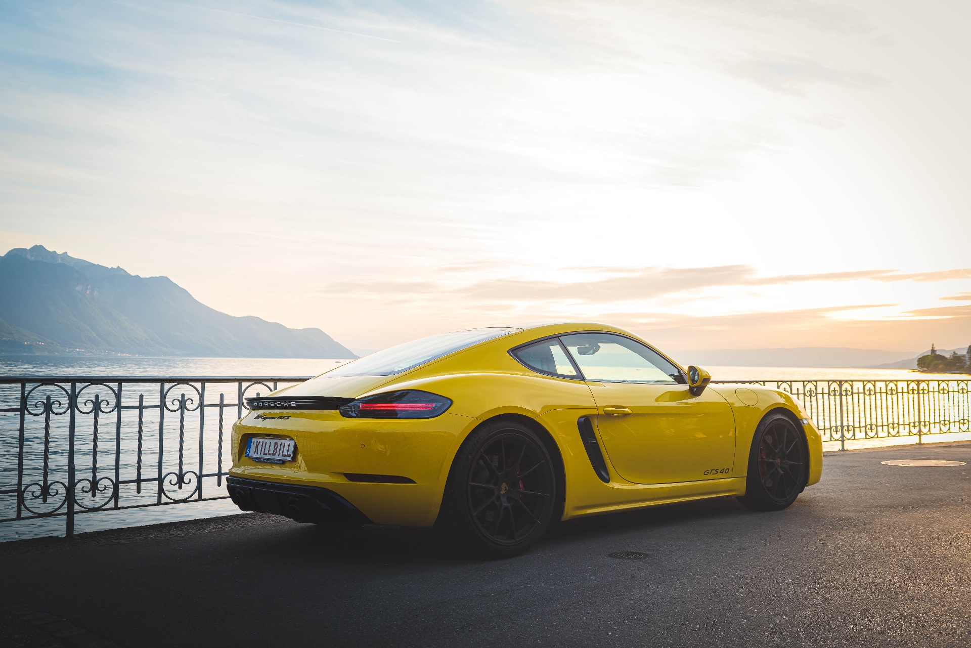 Porsche 718 Cayman GTS jaune au bord du lac au coucher du soleil