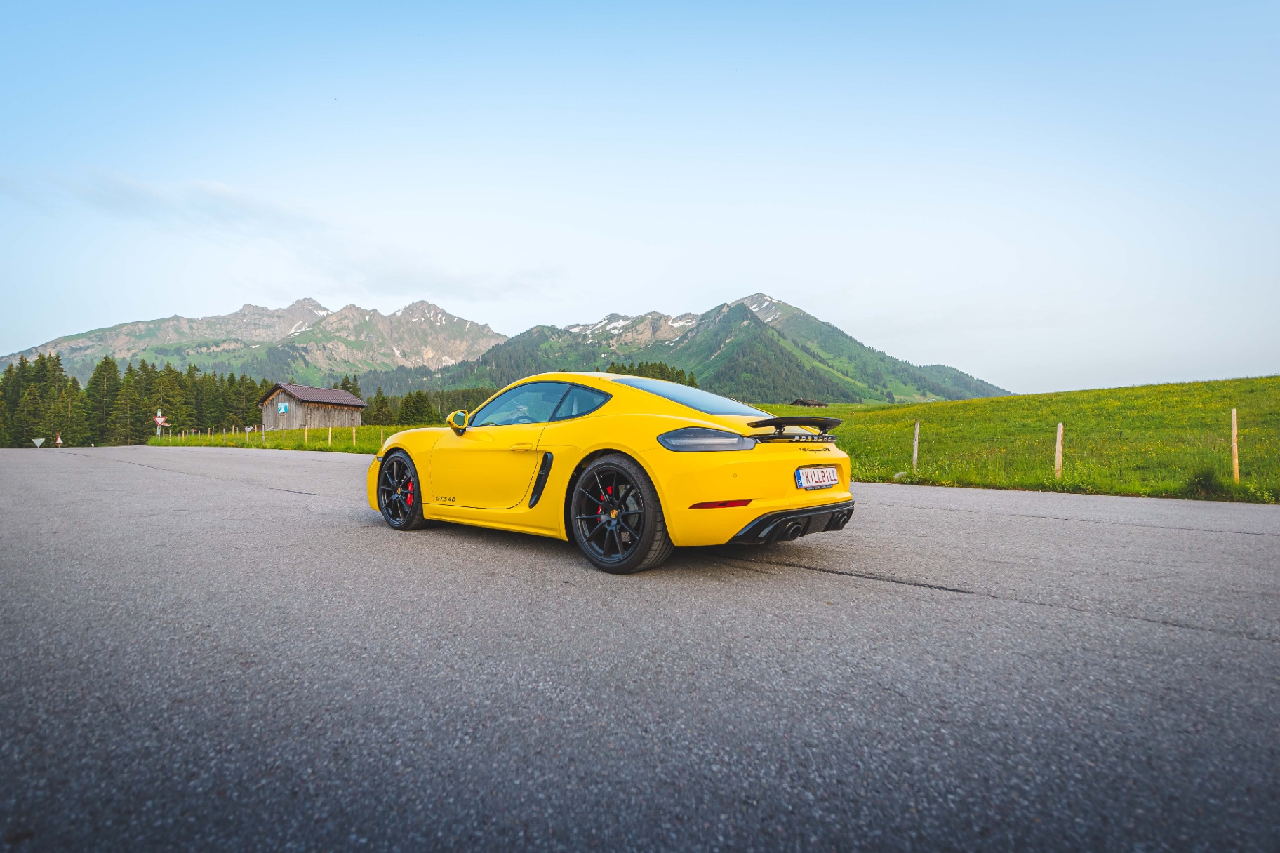 Porsche 718 Cayman GTS jaune isolée sur une route de montagne
