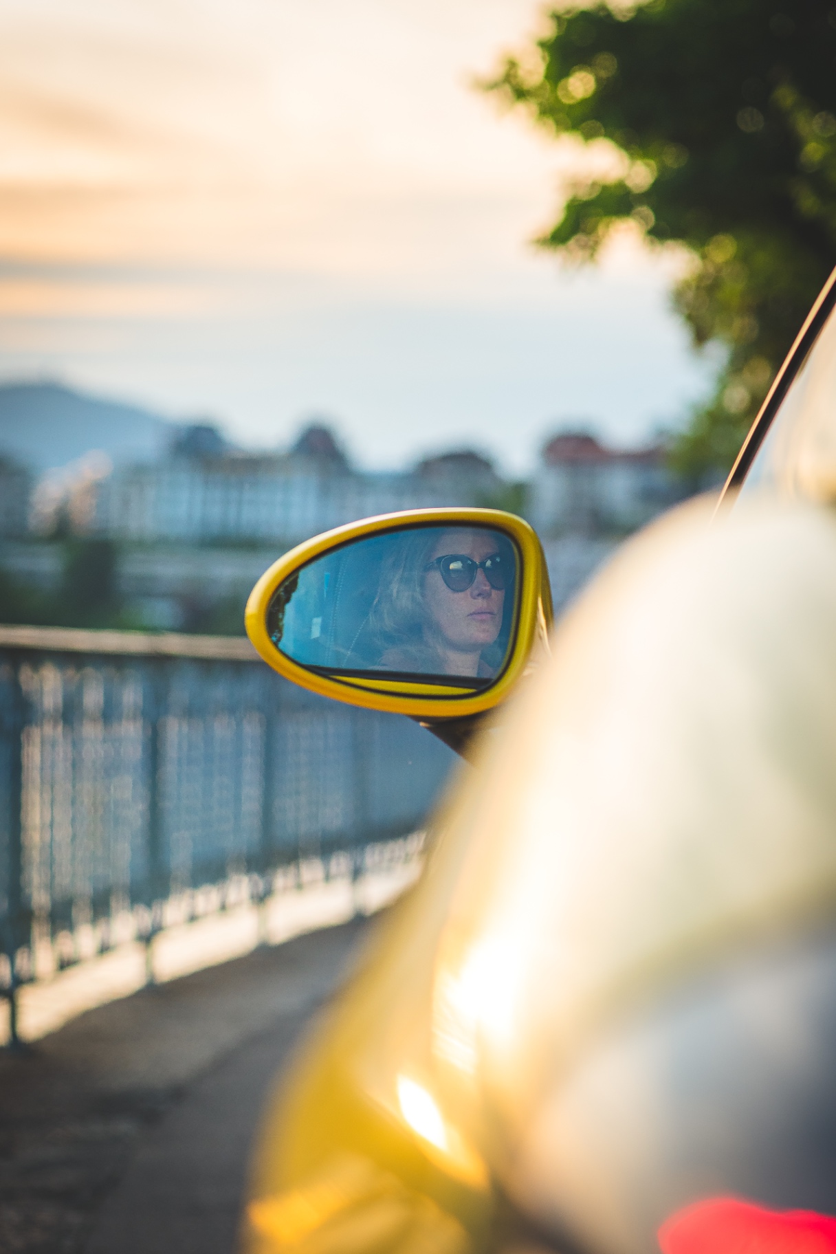 Reflet d'un visage dans le rétroviseur jaune de la Porsche