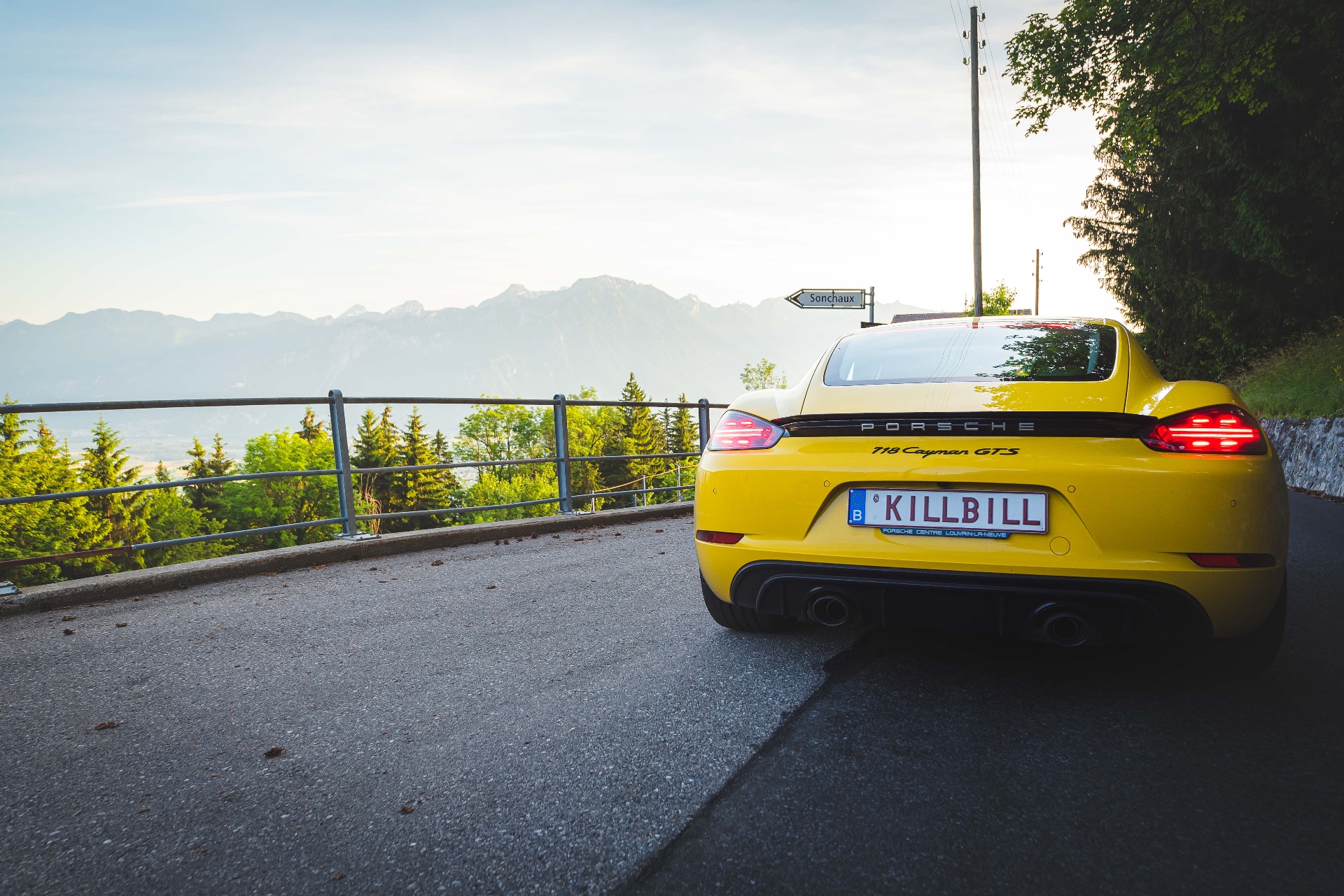 Porsche 718 Cayman GTS jaune vue arrière trois-quarts sur route de montagne